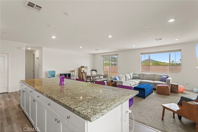 27083 Comrade Cir, Menifee, CA 92585 - kitchen featuring open floor plan, white cabinetry, light stone countertops, recessed lighting, and wood finished floors