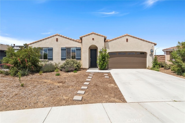 mediterranean / spanish home with stucco siding, driveway, a garage, and a tiled roof