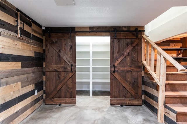 37095 Oak View Rd, Yucaipa, CA 92399 - below grade area featuring a barn door, wood walls, and stairway