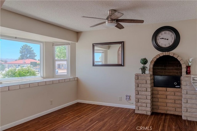 unfurnished living room featuring dark wood finished floors, a textured ceiling, a ceiling fan, and baseboards