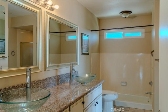 bathroom with double vanity, toilet, and tub / shower combination