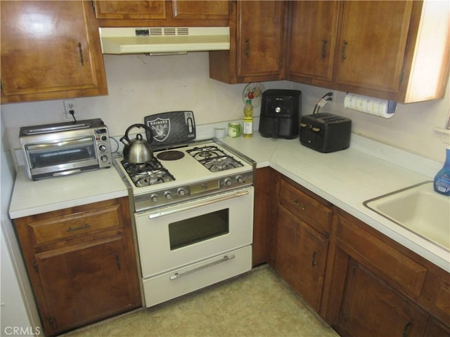 14951 Cactus St, Hesperia, CA 92345 - kitchen with gas range gas stove, under cabinet range hood, light countertops, a sink, and light tile patterned floors