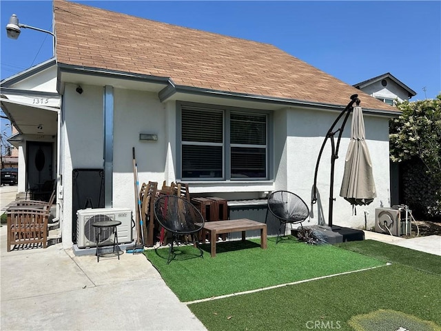 1375-1377 S Cochran Ave Unit 2, Los Angeles, CA 90019 - rear view of house featuring stucco siding, a shingled roof, a lawn, and a cooling unit