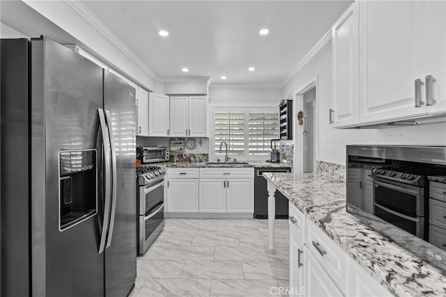 kitchen featuring appliances with stainless steel finishes, a sink, ornamental molding, white cabinetry, and light stone countertops