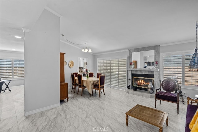dining space with ornamental molding, baseboards, a tiled fireplace, a chandelier, and marble look tiles