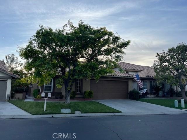1321 Cypress Point Dr, Banning, CA 92220 - view of property hidden behind natural elements featuring a garage, driveway, a tile roof, a front yard, and stucco siding