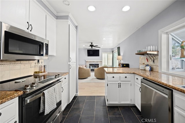 3388 Tonopah St, Oceanside, CA 92054 - kitchen featuring appliances with stainless steel finishes, a fireplace, a ceiling fan, dark tile patterned flooring, and backsplash