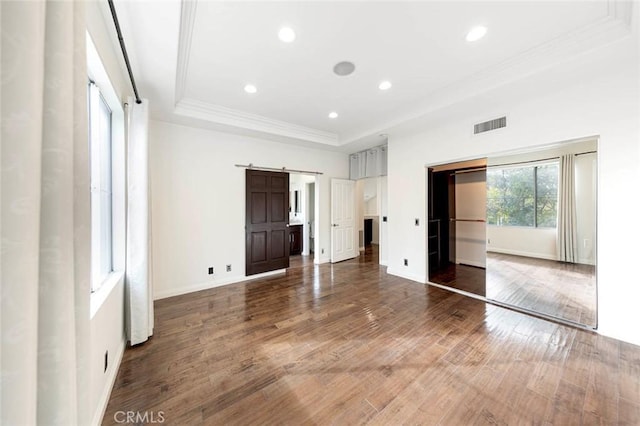 127 Lessay, Newport Coast, CA 92657 - unfurnished bedroom with a barn door, ornamental molding, a raised ceiling, wood finished floors, and baseboards
