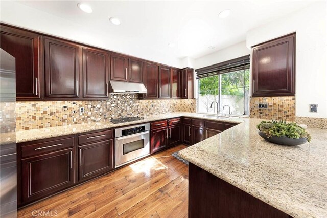 127 Lessay, Newport Coast, CA 92657 - kitchen with appliances with stainless steel finishes, under cabinet range hood, a sink, light stone counters, and recessed lighting