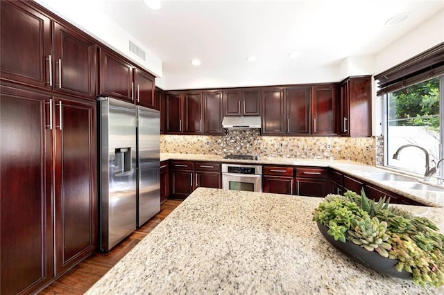 127 Lessay, Newport Coast, CA 92657 - kitchen featuring stainless steel appliances, under cabinet range hood, a sink, light stone countertops, and dark brown cabinets