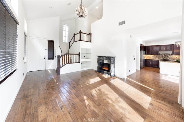 127 Lessay, Newport Coast, CA 92657 - unfurnished living room featuring a towering ceiling, stairs, wood finished floors, a chandelier, and baseboards