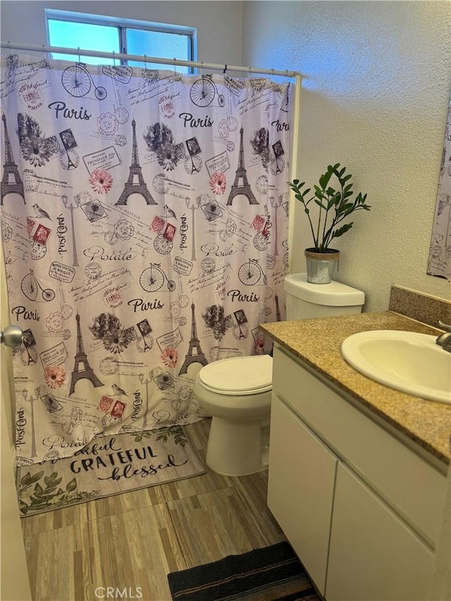 455 Cherry Ln Unit K, Manteca, CA 95337 - bathroom featuring toilet, a textured wall, vanity, wood finished floors, and curtained shower