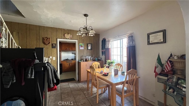 dining area with a chandelier, wood walls, and stairs