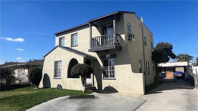 view of front of property with a balcony, stucco siding, and cooling unit