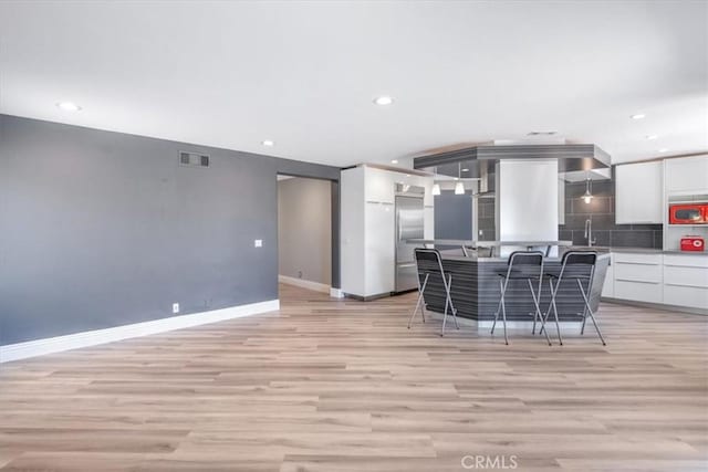 16 Vistamar Dr, Laguna Niguel, CA 92677 - kitchen featuring modern cabinets, white cabinets, light wood-style flooring, decorative backsplash, and a center island