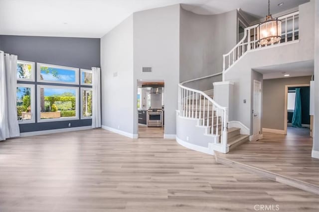 16 Vistamar Dr, Laguna Niguel, CA 92677 - unfurnished living room featuring high vaulted ceiling, a chandelier, wood finished floors, and stairway