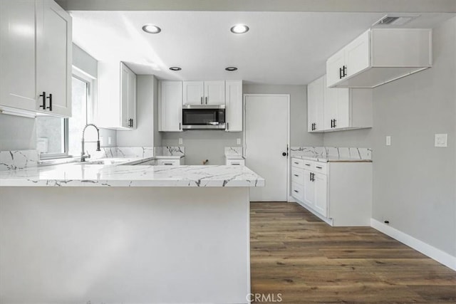 1840 E Hawthorne St, Ontario, CA 91764 - kitchen featuring stainless steel microwave, a peninsula, dark wood finished floors, a sink, and light stone countertops