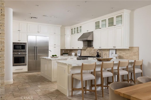 110 Via Orvieto, Newport Beach, CA 92663 - kitchen with built in appliances, under cabinet range hood, a peninsula, decorative backsplash, and a breakfast bar