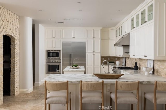 110 Via Orvieto, Newport Beach, CA 92663 - kitchen with built in appliances, under cabinet range hood, decorative backsplash, a peninsula, and recessed lighting