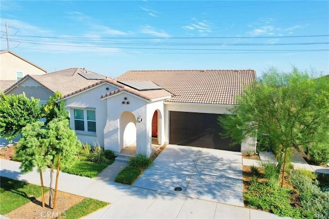 3410 E Foxglove Way, Ontario, CA 91761 - mediterranean / spanish-style house with a tiled roof, driveway, an attached garage, roof mounted solar panels, and stucco siding