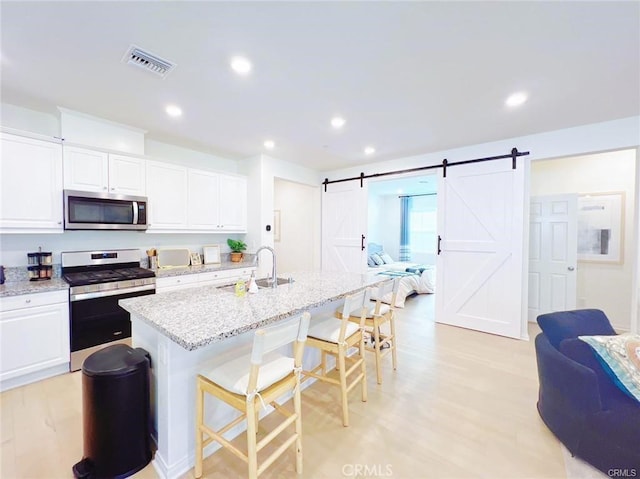 3410 E Foxglove Way, Ontario, CA 91761 - kitchen featuring stainless steel appliances, a sink, a breakfast bar, open floor plan, and light stone countertops