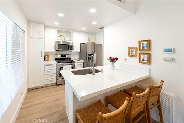 28107 Caldaro, Laguna Niguel, CA 92677 - kitchen featuring stainless steel appliances, a kitchen breakfast bar, a peninsula, light wood finished floors, and a sink