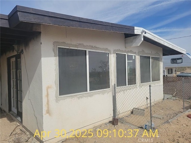 view of side of home featuring fence and stucco siding