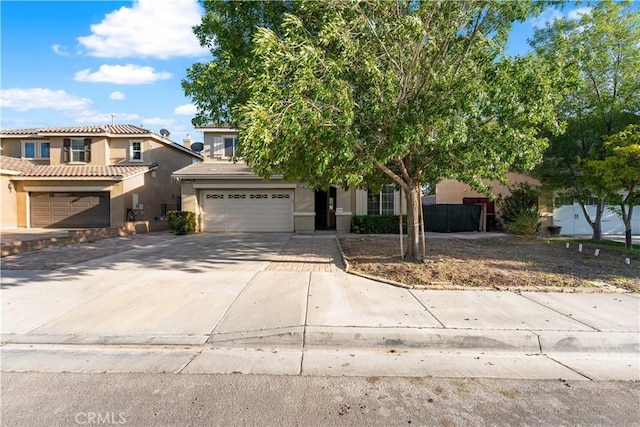 view of front of house featuring stucco siding, concrete driveway, an attached garage, and fence