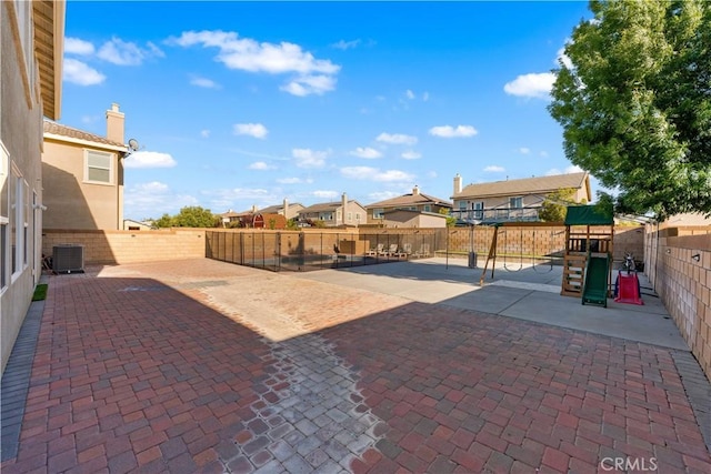 view of patio / terrace featuring a playground, central air condition unit, a fenced backyard, and a residential view