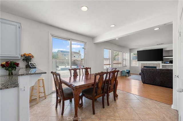 dining space featuring light tile patterned floors, a tiled fireplace, and recessed lighting