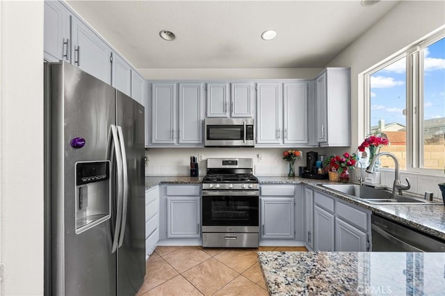 kitchen with stainless steel appliances, a sink, light tile patterned floors, stone countertops, and recessed lighting