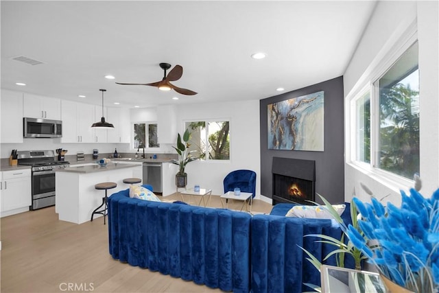 34582 Calle Rosita, Dana Point, CA 92624 - living room featuring light wood finished floors, a warm lit fireplace, a ceiling fan, and recessed lighting