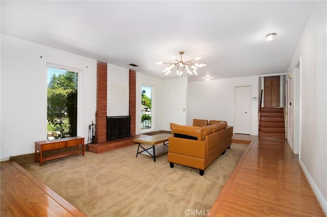 living area with a chandelier, light wood-style floors, stairs, and a fireplace