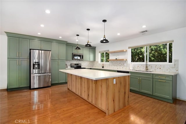 kitchen featuring appliances with stainless steel finishes, green cabinetry, a sink, backsplash, and light countertops