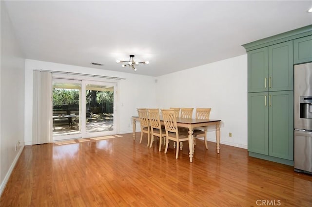 dining room featuring a chandelier, light wood-style flooring, and baseboards
