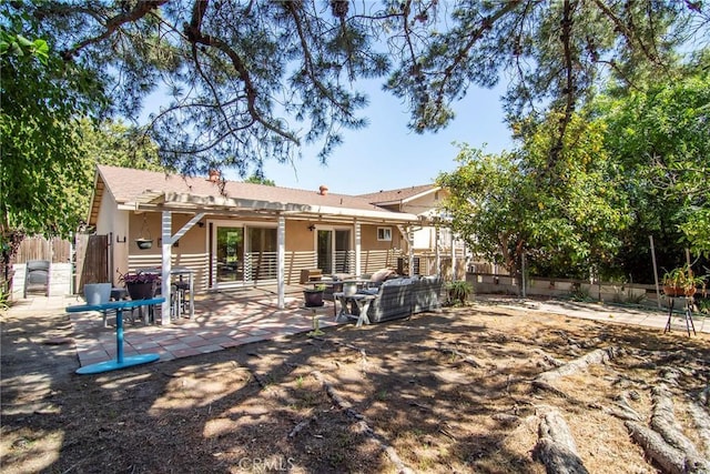 rear view of property featuring fence, a patio area, and stucco siding