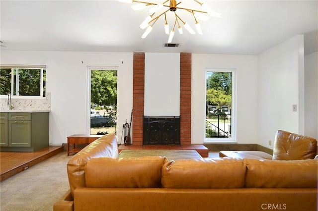 living area featuring a chandelier, plenty of natural light, a fireplace, and light colored carpet