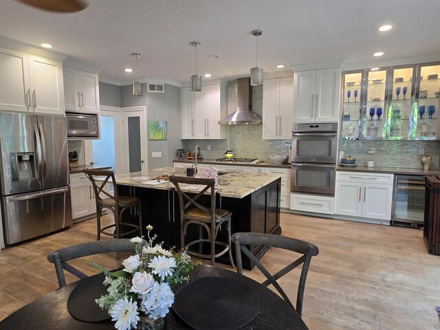 11610 Wills Creek Rd, San Diego, CA 92131 - kitchen featuring stainless steel appliances, wall chimney exhaust hood, wine cooler, backsplash, and light wood finished floors