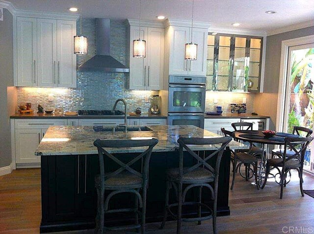 11610 Wills Creek Rd, San Diego, CA 92131 - kitchen with wall chimney range hood, double oven, a sink, dark wood-type flooring, and tasteful backsplash