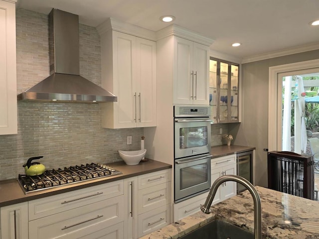 11610 Wills Creek Rd, San Diego, CA 92131 - kitchen with wall chimney range hood, appliances with stainless steel finishes, beverage cooler, tasteful backsplash, and white cabinets