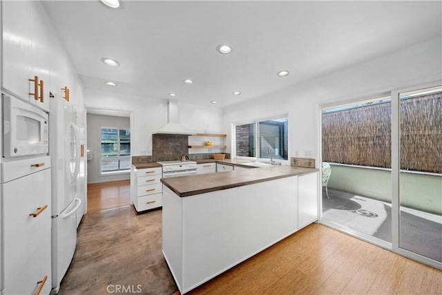 16851 Morse Cir, Huntington Beach, CA 92649 - kitchen featuring wall chimney exhaust hood, white appliances, a sink, white cabinets, and a peninsula