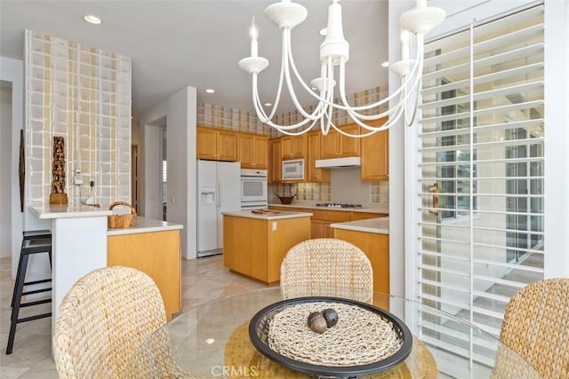 75929 Camino Cielo, Indian Wells, CA 92210 - kitchen with white appliances, a chandelier, a kitchen island, under cabinet range hood, and light countertops