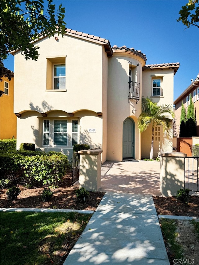 13529 Scarlet Sage Trl, San Diego, CA 92130 - mediterranean / spanish house featuring a balcony, stucco siding, fence, a gate, and a tile roof