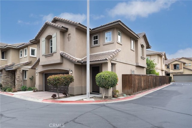 8063 Cambria Cir, Stanton, CA 90680 - townhome / multi-family property featuring an attached garage, fence, stucco siding, and a tiled roof