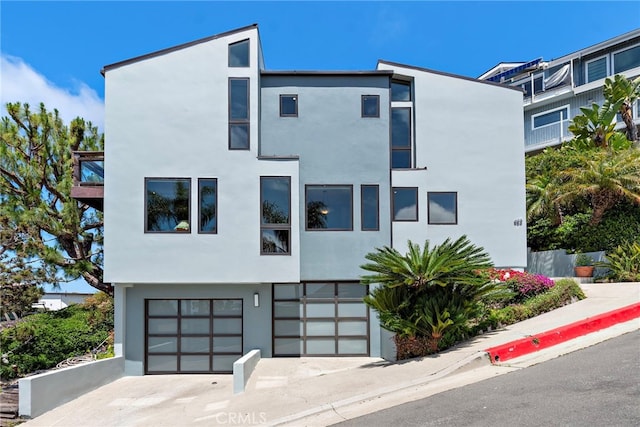 contemporary house featuring stucco siding, an attached garage, and concrete driveway
