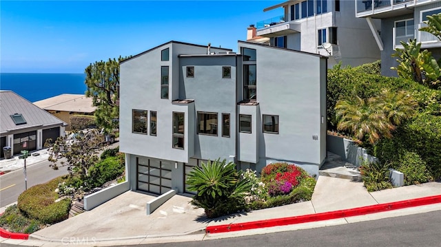 view of property with a garage, a water view, and concrete driveway