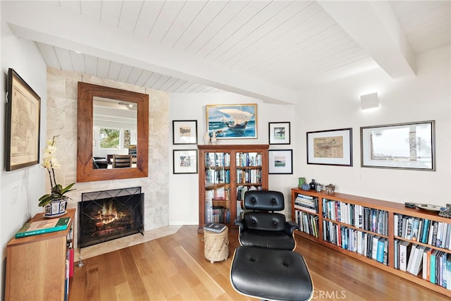 sitting room with beam ceiling, wood ceiling, wood finished floors, and a tiled fireplace
