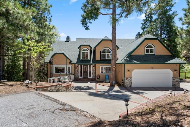 26061 Augusta Dr, Lake Arrowhead, CA 92391 - view of front of house featuring driveway, a chimney, stone siding, and a shingled roof