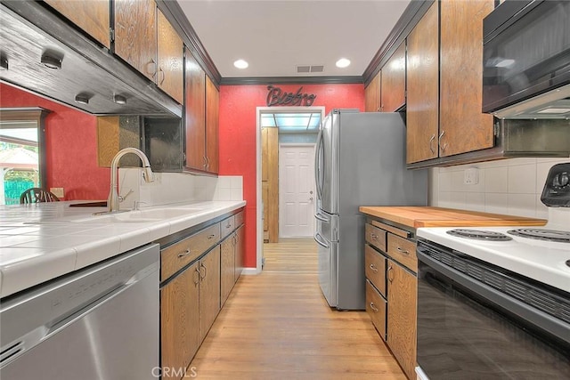 1244 N Albright Ave, Upland, CA 91786 - kitchen featuring appliances with stainless steel finishes, a sink, light wood-type flooring, tile counters, and crown molding