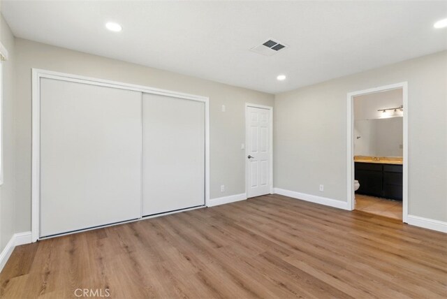 56620 Hidden Gold Dr, Yucca Valley, CA 92284 - unfurnished bedroom with light wood-type flooring, a closet, baseboards, recessed lighting, and connected bathroom